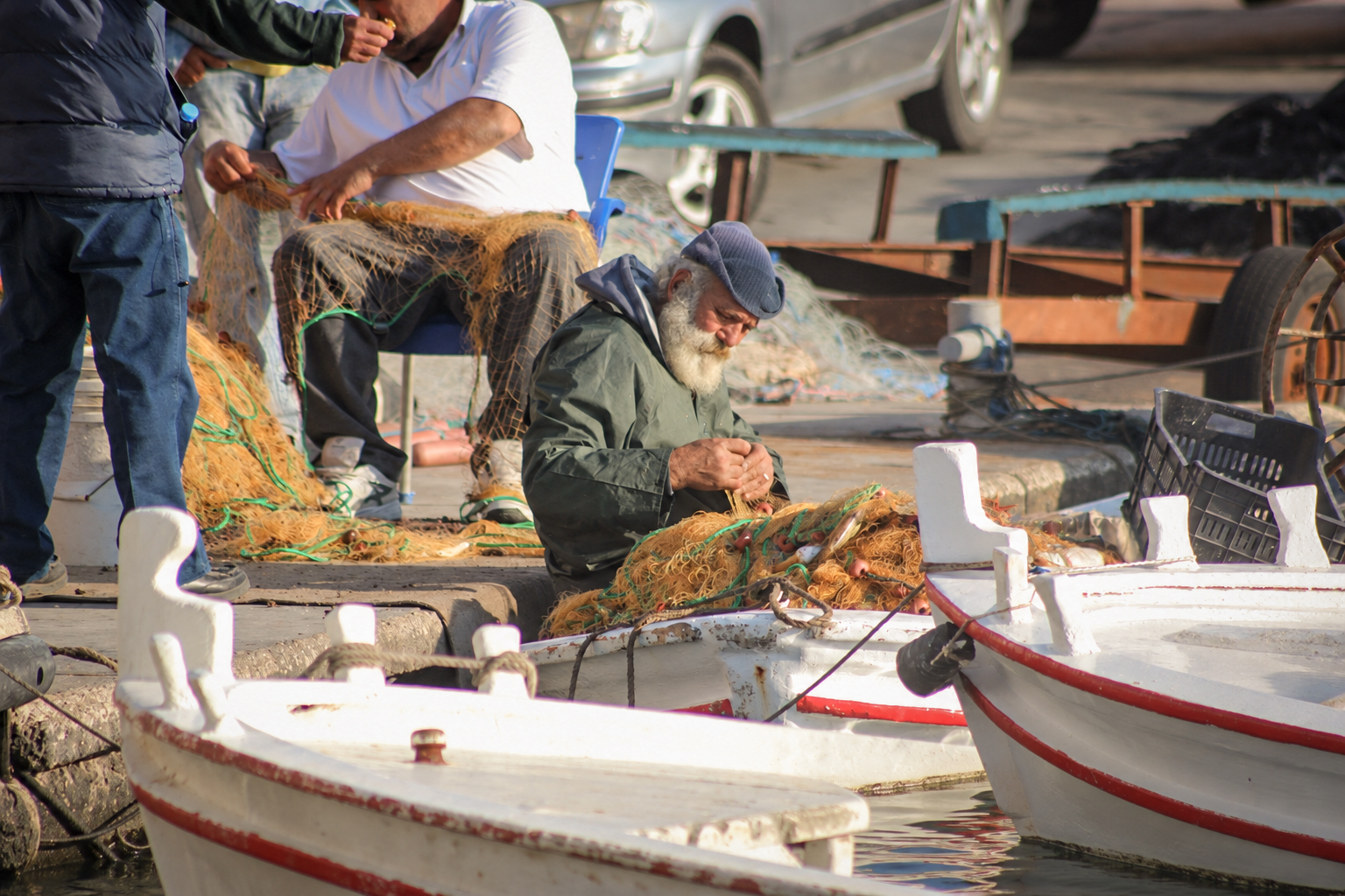Fishermen mending nets among the moored boats