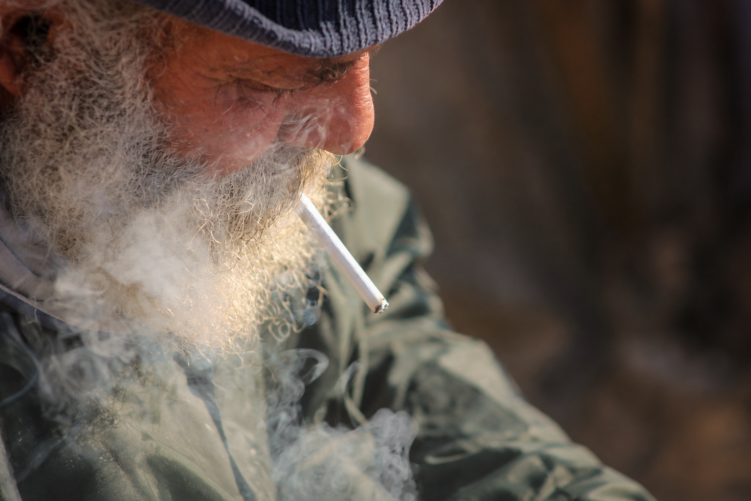 A fisherman with a white beard and a cigarette, in profile